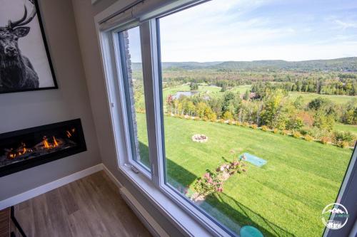 une grande fenêtre avec vue sur un champ vert dans l'établissement Les Rois de la Montagne, à Saint-Jean-de-Matha