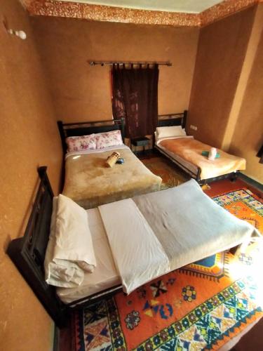 a room with two beds and a rug at auberge restaurant tizgui in Tinerhir