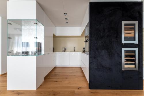 a kitchen with white cabinets and a black wall at Exclusive 2BR Skyline Penthouse by HM in Vienna