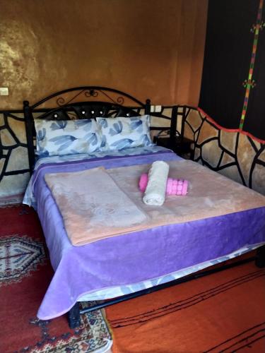 a bed with purple sheets and pink candles on it at auberge restaurant tizgui in Tinerhir