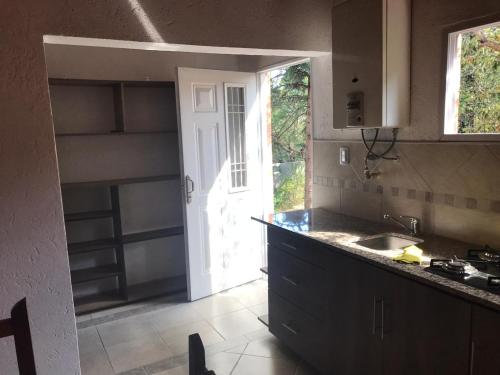 cocina con encimera, fregadero y puerta en El Jacaranda 2 - Complejo en Agua de Oro