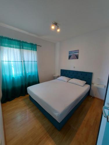 una camera con un grande letto con testiera blu di Apartmani Vlahušić a Putniković