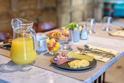 a table with a plate of food and a jug of orange juice at Saint Georges Hotel & Spa in Chalon-sur-Saône