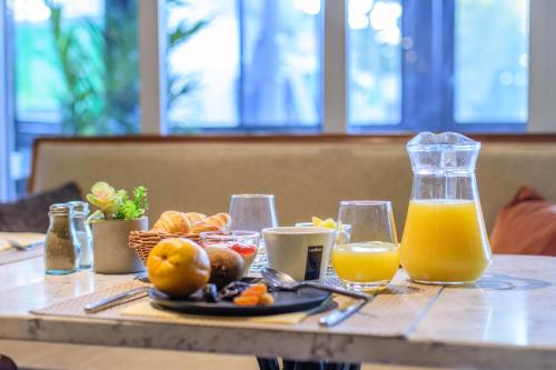 a table with a plate of food and orange juice at Saint Georges Hotel & Spa in Chalon-sur-Saône