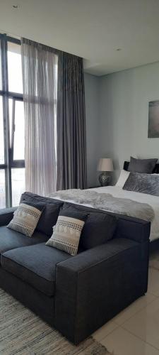 a large bed with a blue couch in a bedroom at Studio 1101 iTower in Gaborone