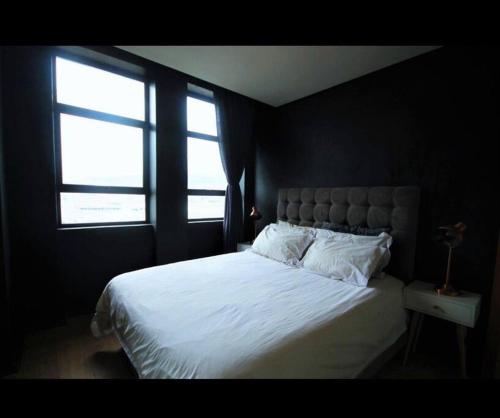 a bedroom with a large white bed with two windows at Fountain Suites Aparthotel - PRIVATE in Cape Town