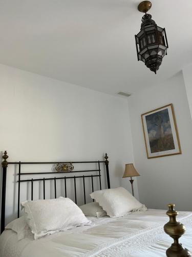 1 dormitorio con 1 cama con sábanas blancas y lámpara en Casa Cas, en Jerez de la Frontera