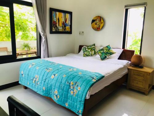 um quarto com uma cama com um cobertor azul em Sophia Homestay Hoi An em Hoi An