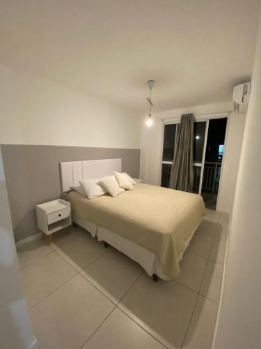 a white bedroom with a bed and a window at Mediterrâneo 507 - Todo Equipado, Ar Condicionado, Churrasqueira na Varanda, Internet Fibra 600MB, Estacionamento Grátis in Cabo Frio
