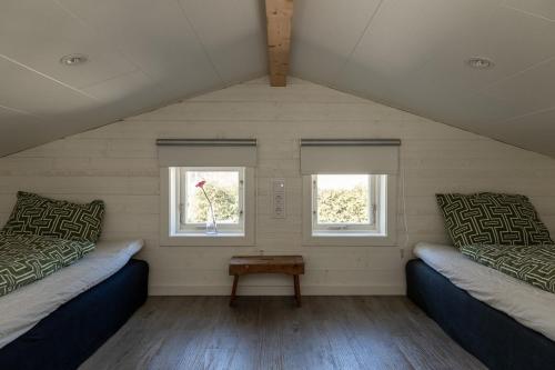 a attic room with two beds and two windows at Havsstugan in Sölvesborg