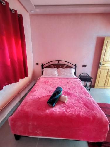 Un dormitorio con una cama roja con un teléfono. en auberge restaurant tizgui, en Tinerhir