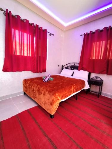 a bedroom with a large bed with red curtains at auberge restaurant tizgui in Tinerhir