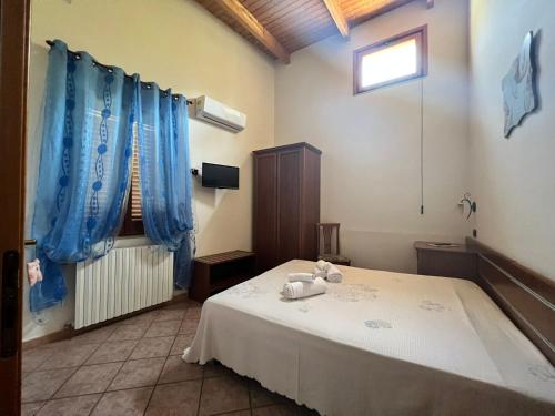 1 dormitorio con 1 cama con cortinas azules y ventana en Agriturismo A do' Cumparone, en Corbara