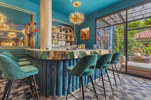 Don Rafa Boutique Hotel & Residences في سان خوان: بار مع كراسي خضراء في غرفة بجدران زرقاء