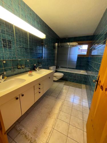 een badkamer met 2 wastafels, een toilet en een bad bij Chalet Alten in Klosters Dorf