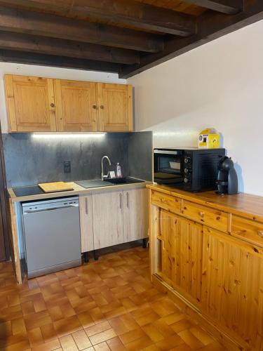 una cucina con armadi in legno, lavandino e forno a microonde di APPARTEMENT VUE SUR LES PISTES Aux SAISIES 4 a Les Saisies