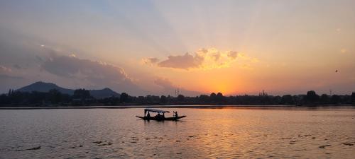 a boat on the water with a sunset in the background at Lily Of The World Houseboat in Srinagar