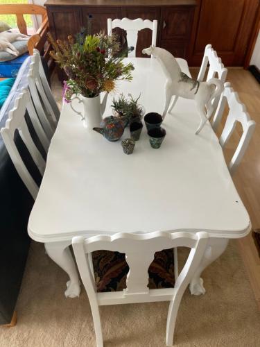 a white table with chairs and plants on it at Two Oceans Artist's Home. in Fish hoek