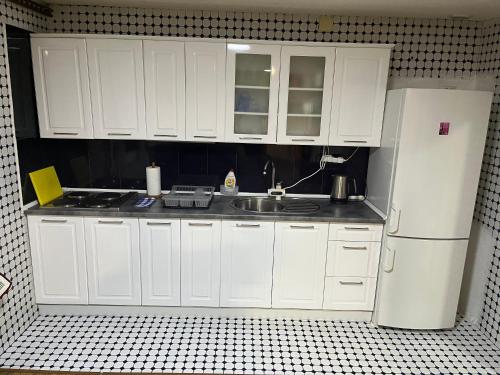 a kitchen with white cabinets and a sink and a refrigerator at Apartman House Jasmina in Bihać
