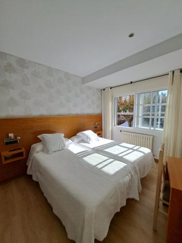 Un dormitorio con una gran cama blanca y una ventana en Hotel Casa Román, en Sanxenxo