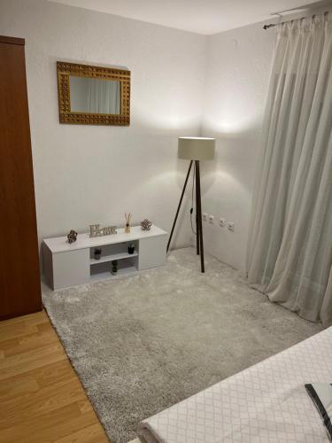 a white living room with a table and a lamp at Apartman House Jasmina in Bihać