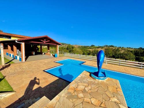 a house with a swimming pool with a blue pool at Chácara com 4 Chalés, grande piscina e muito verde in Atibaia