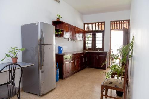 kuchnia z lodówką ze stali nierdzewnej i drewnianymi szafkami w obiekcie Greenscape Colombo w Kolombo