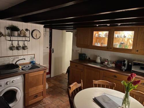 a kitchen with a table and a sink and a washing machine at Isallt Cosy Cottage. Dogs Welcome. Superking & Double Bed. Log Burner. Peaceful Village Location in Llanbrynmair