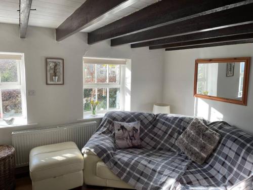 a living room with a couch with a blanket at Isallt Cosy Cottage. Dogs Welcome. Superking & Double Bed. Log Burner. Peaceful Village Location in Llanbrynmair