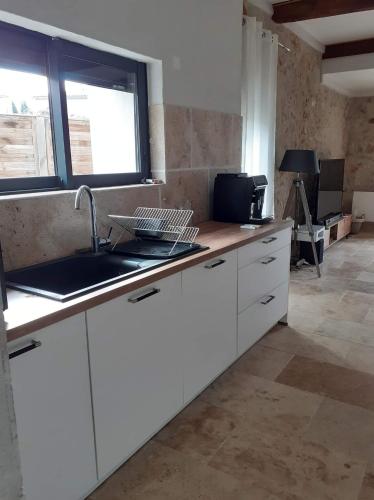 une cuisine avec des armoires blanches et un évier dans l'établissement maison a bizanet avec piscine, à Bizanet