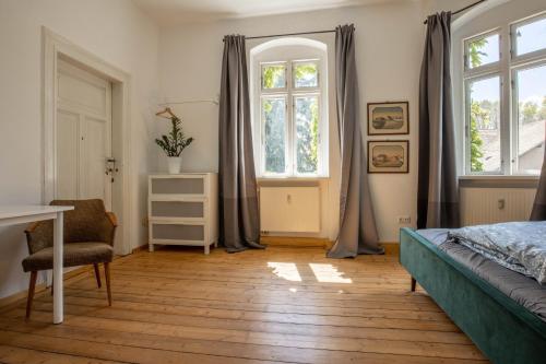 um quarto com uma cama, uma secretária e janelas em Zeitreise: Wohnen im Herrenhaus genau zw. L u. DD em Mügeln