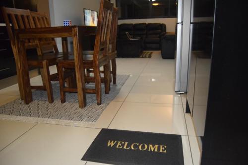 ウィントフークにあるScenic Apartment in Windhoek City Centreの椅子とテーブルのある床に敷かれたウェルカムマット
