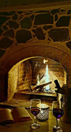 two glasses of wine on a table with a fireplace at Orionas in Tsoútsouros