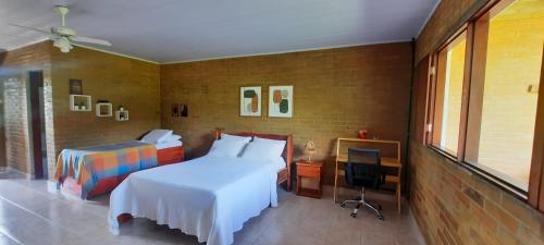 a bedroom with a bed and a desk and a television at Eco Flat 314 - Hotel Fazenda Pedra do Rodeadoro in Bonito
