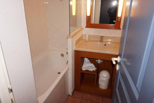 une salle de bain avec un lavabo, une baignoire et un miroir dans l'établissement La Pinède Golf, Surf, Vélo, Piscine, à Lacanau