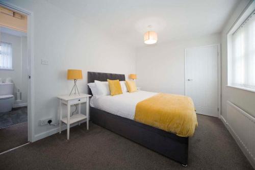 a bedroom with a bed with a yellow blanket on it at Marlborough Cottage in Stockton-on-Tees