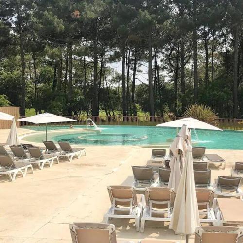 un groupe de chaises et de parasols à côté d'une piscine dans l'établissement La Pinède Golf, Surf, Vélo, Piscine, à Lacanau