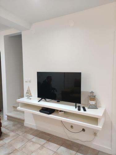 a white wall with a large television on it at Costa House in Nazaré