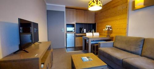 een woonkamer met een bank en een keuken bij Lune D'Argent Appartement avec vue sur la montagne in Megève