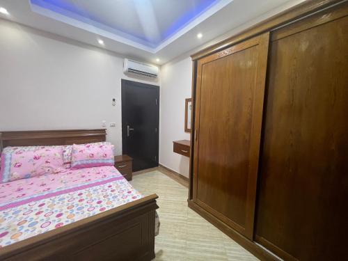 a bedroom with a bed and a large wooden cabinet at Compound cecelia families only in Hurghada