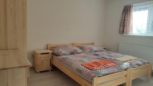 a bedroom with a bed with a night stand and a window at Privat Liska in Liptovský Mikuláš