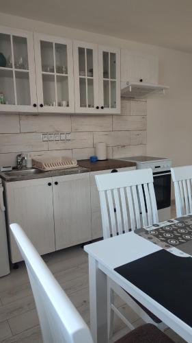 a kitchen with white cabinets and a table and chairs at Privat Liska in Liptovský Mikuláš