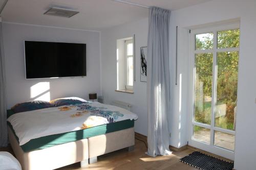 1 dormitorio con 1 cama y TV en la pared en Ferienwohnung Elbtal Meißen, Dresden, Moritzburg en Weinböhla