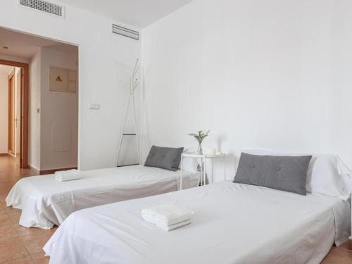 Duas camas num quarto com paredes brancas em Alojamiento con piscina y parking en Sevilla em La Algaba