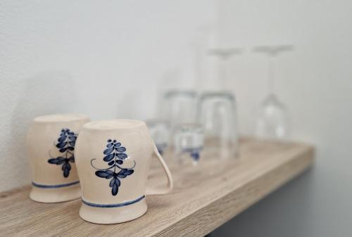 three cups sitting on a wooden counter with glasses at Apartmány Minoris in Liptovský Mikuláš