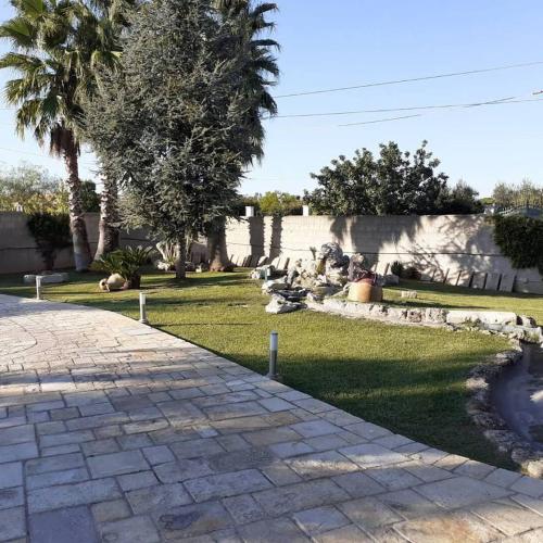 un jardín con un camino de piedra, árboles y una pared en B&B Bedafè, en Arnesano