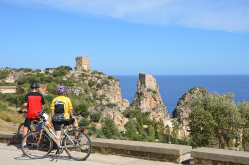 two people riding bikes on a road near the ocean at Villa delle Stelle in Scopello