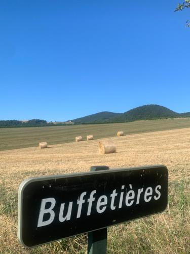 a sign in front of a field with hay bales at Le Gîte de Buffetières in Saint-Romain-de-Popey