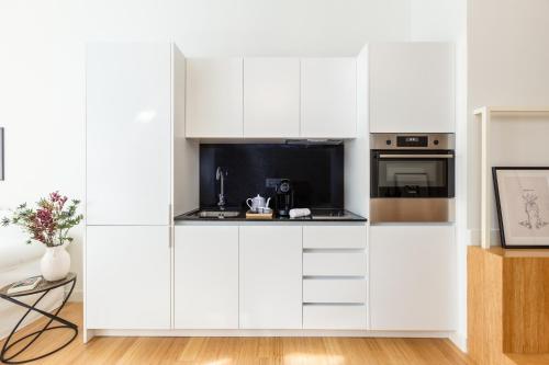 a white kitchen with white cabinets at Welcome Aliados a Noble apartment in City Heart in Porto