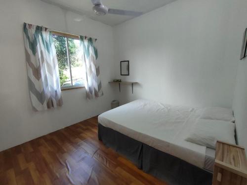 a white bedroom with a bed and a window at Orchard View Guesthouse Tambunan in Tambunan